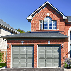 brick home with rounded entrance and gray garage doors