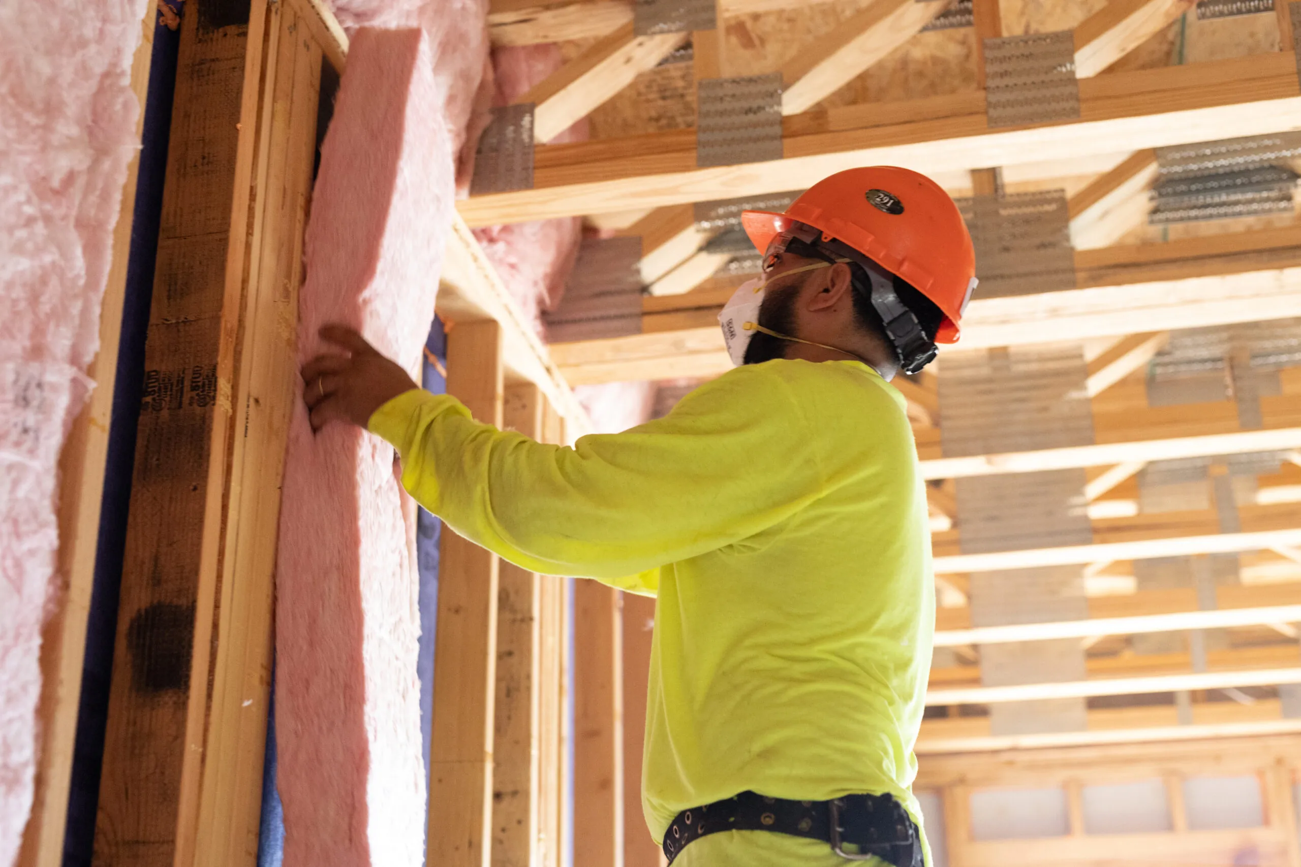 Man installing fiberglass batts into wall
