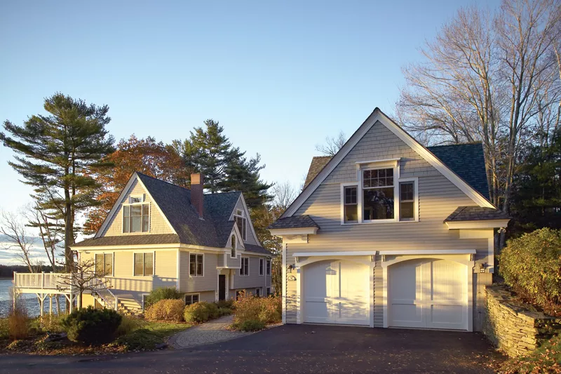 Lakeside A-frame home with detached garage with two white windowless garage doors.