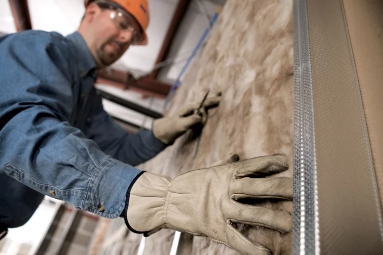 Man installing fiberglass insulation in a new home construction project
